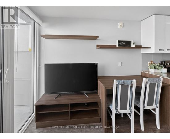 A modern living room with a television and two chairs.