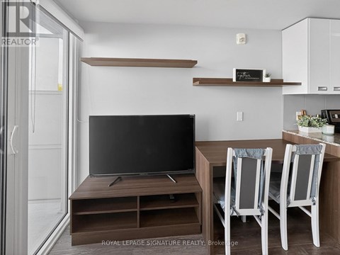 A modern living room with a television and two chairs.