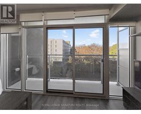 A glass door with a handle and a window with a view of a building and trees.