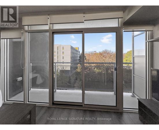 A glass door with a handle and a window with a view of a building and trees.