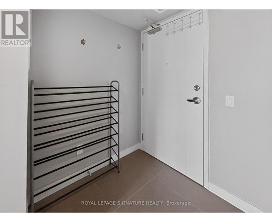 A white door is closed in a room with a metal rack on the wall.