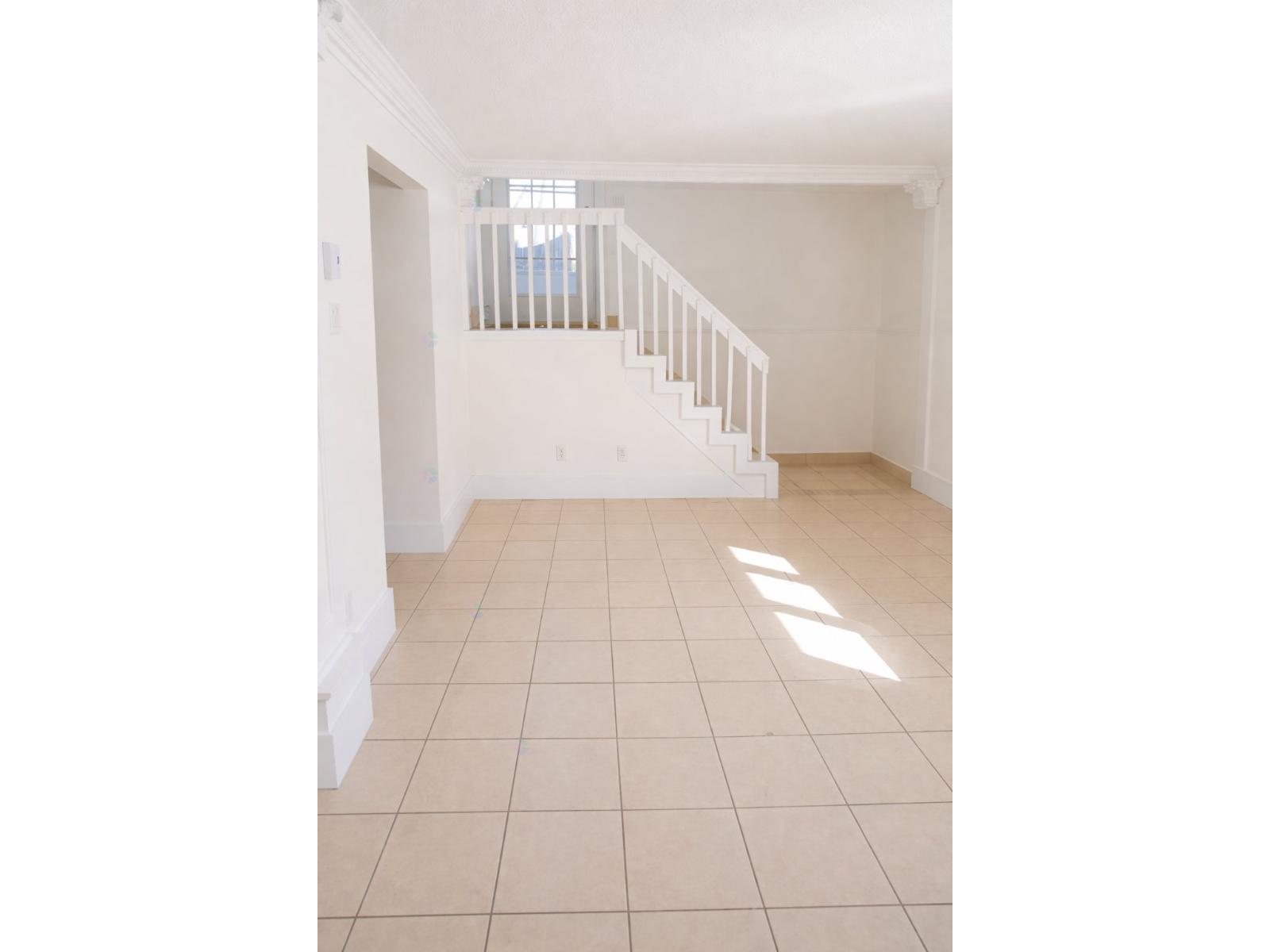 A white hallway with a tiled floor and a staircase.