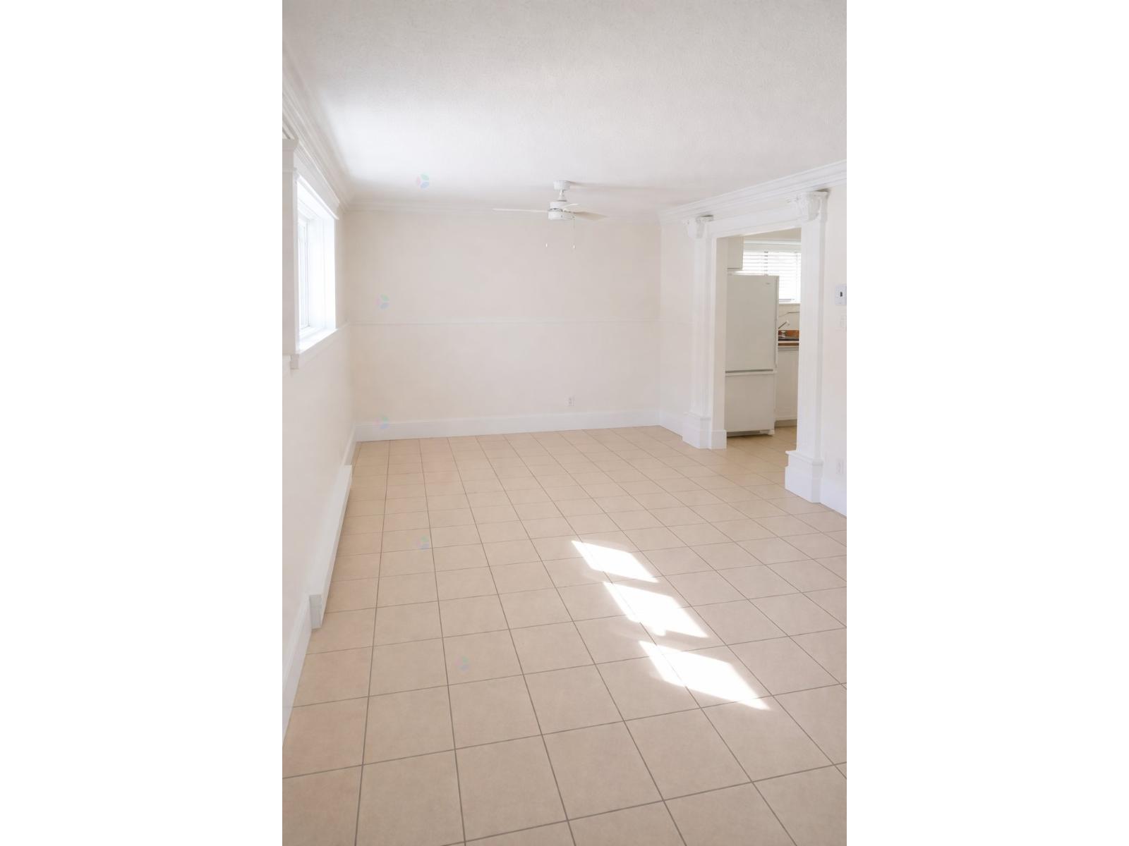A white room with tiled flooring and a doorway leading to another room.