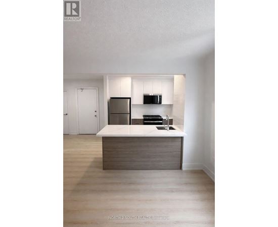 A modern kitchen with a wooden island and stainless steel appliances.