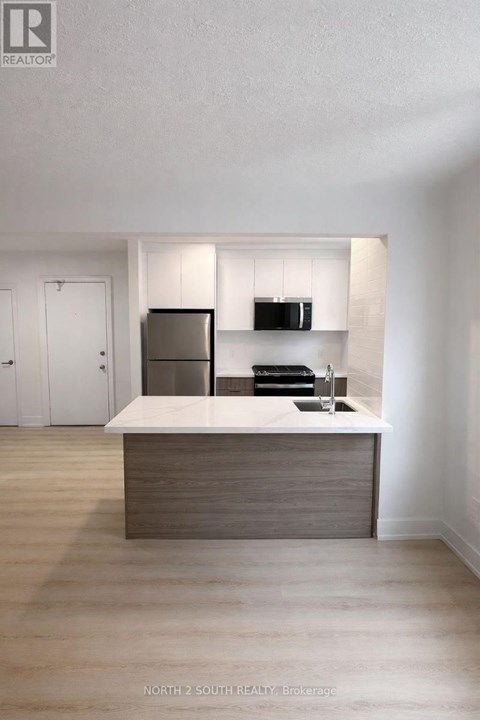 A modern kitchen with a wooden island and stainless steel appliances.