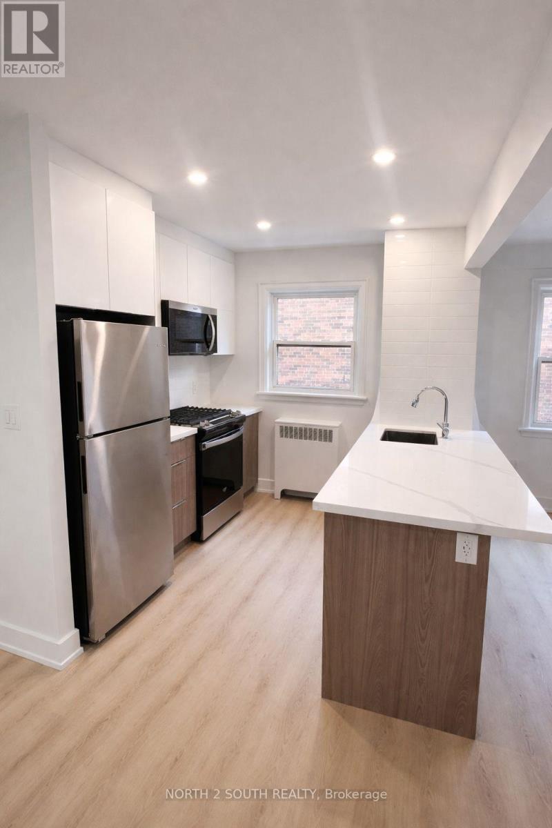 A kitchen with a refrigerator, microwave, and sink.