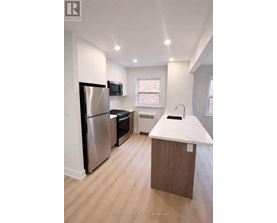A kitchen with a refrigerator, microwave, and sink.