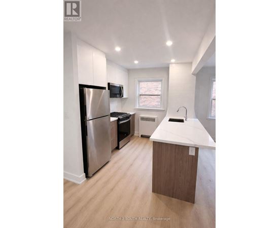 A kitchen with a refrigerator, microwave, and sink.