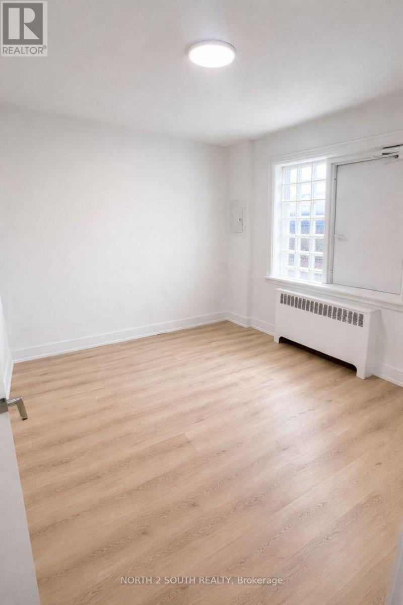 A room with wooden flooring and a window with a white frame.