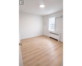 A room with wooden flooring and a window with a white frame.