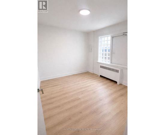 A room with wooden flooring and a window with a white frame.