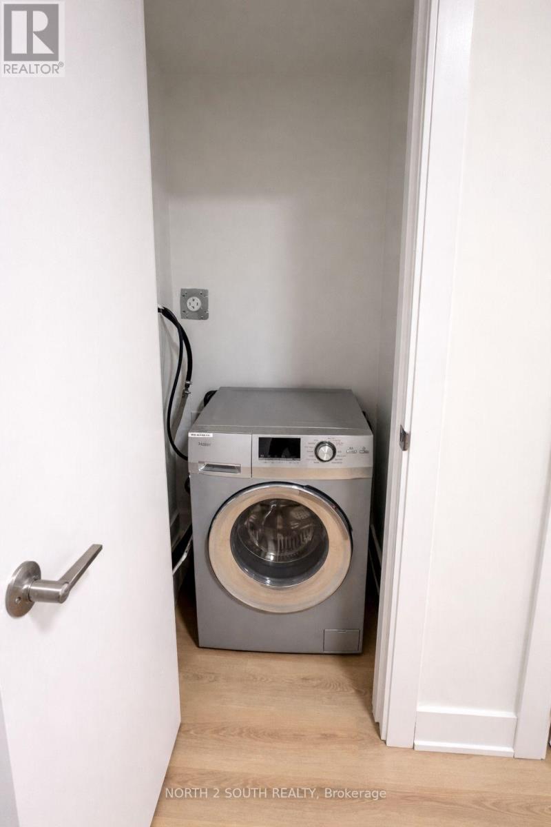 A washing machine is in a small space between two walls.