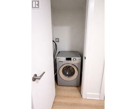 A washing machine is in a small space between two walls.