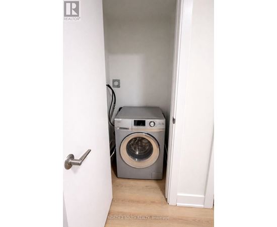 A washing machine is in a small space between two walls.
