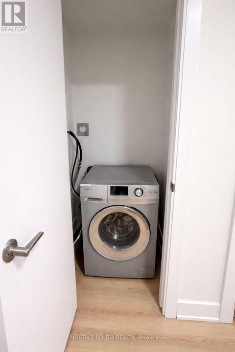 A washing machine is in a small space between two walls.
