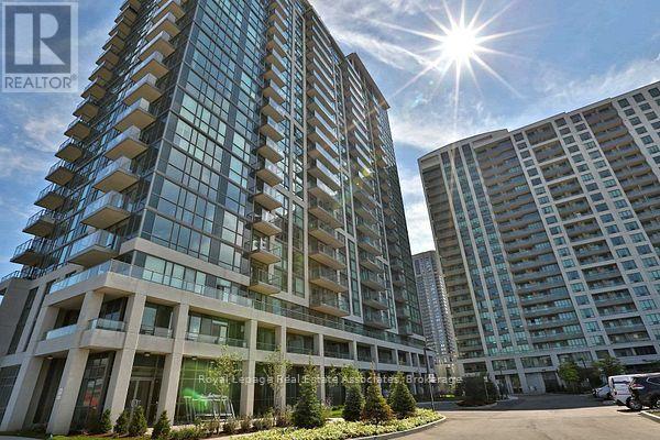 A modern multi-story building with a glass facade and a sunny sky above.