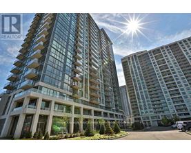 A modern multi-story building with a glass facade and a sunny sky above.