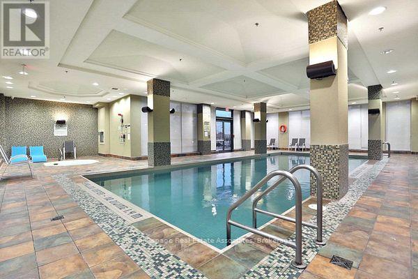 A large indoor swimming pool with a tiled floor and a stone border.