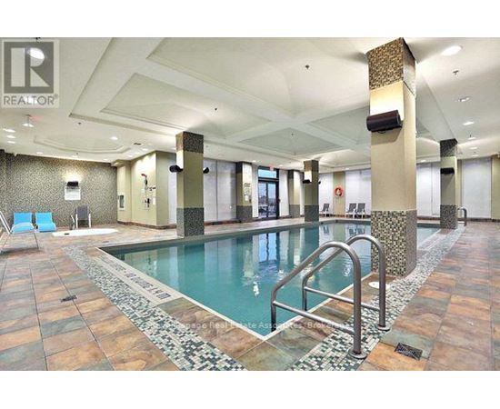 A large indoor swimming pool with a tiled floor and a stone border.