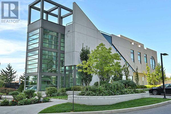A modern building with a glass facade and a landscaped front yard.