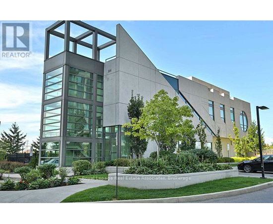 A modern building with a glass facade and a landscaped front yard.