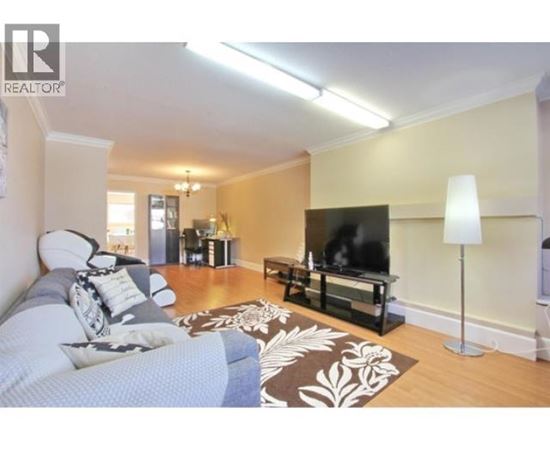 A living room with a grey couch and a black television.
