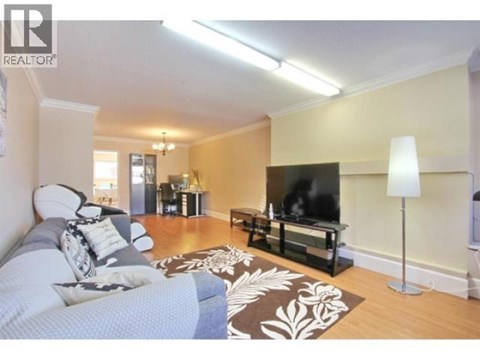 A living room with a grey couch and a black television.