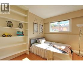A bedroom with a bed, a window, and a shelf with toys on it.