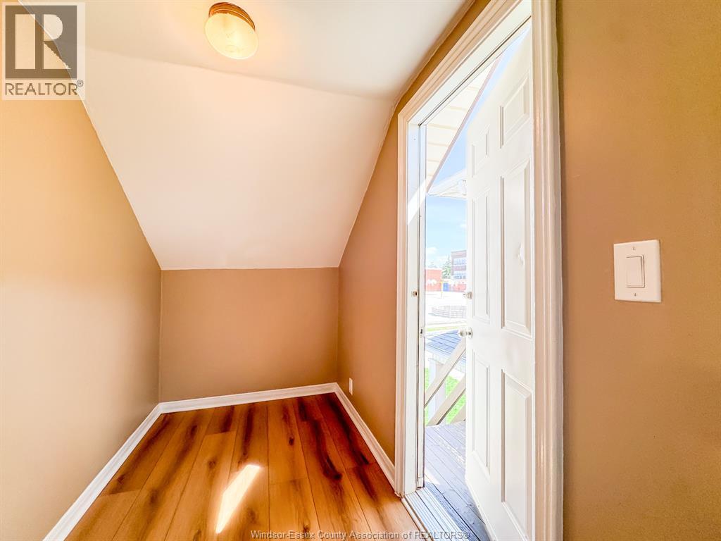 A room with a wooden floor and a door leading outside.