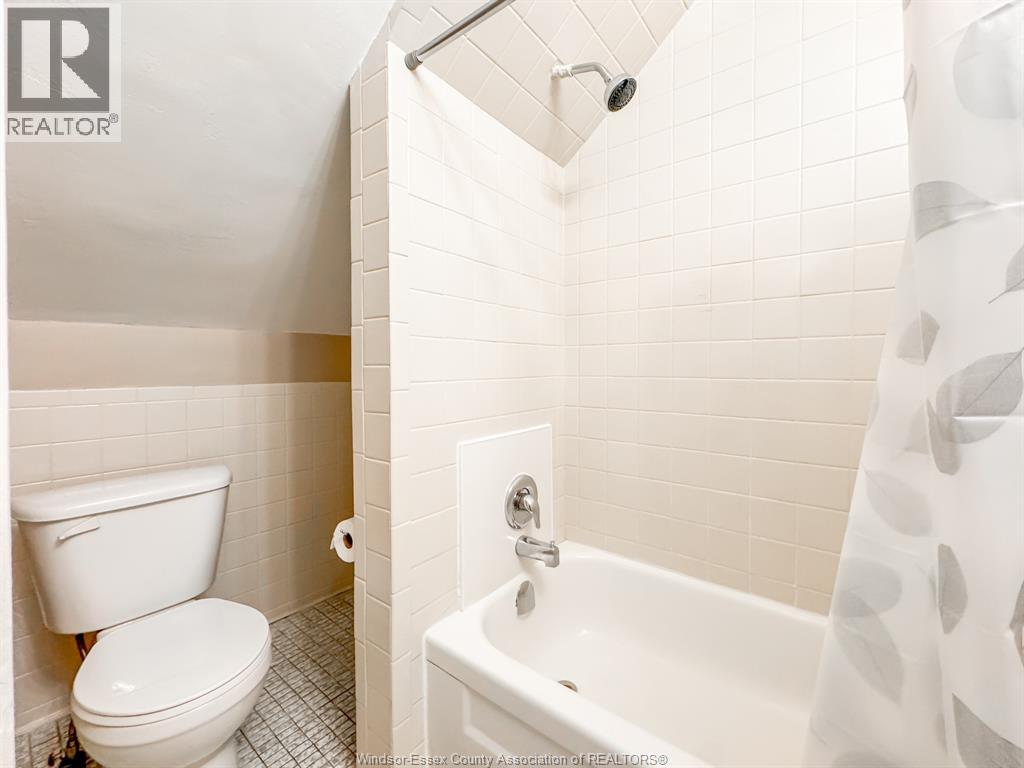 A white toilet sits next to a white bathtub in a bathroom.