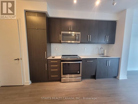 A kitchen with dark wood cabinets and stainless steel appliances.