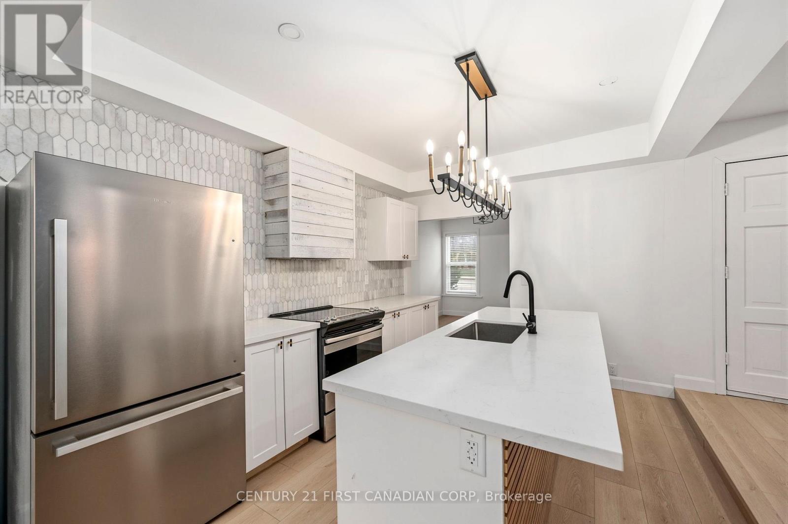 A modern kitchen with a stainless steel refrigerator and a white island.