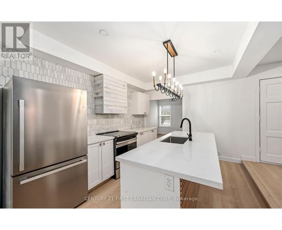 A modern kitchen with a stainless steel refrigerator and a white island.