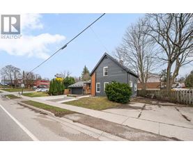 A grey house with a white fence in front of it.