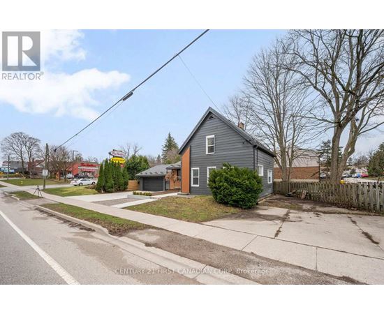 A grey house with a white fence in front of it.