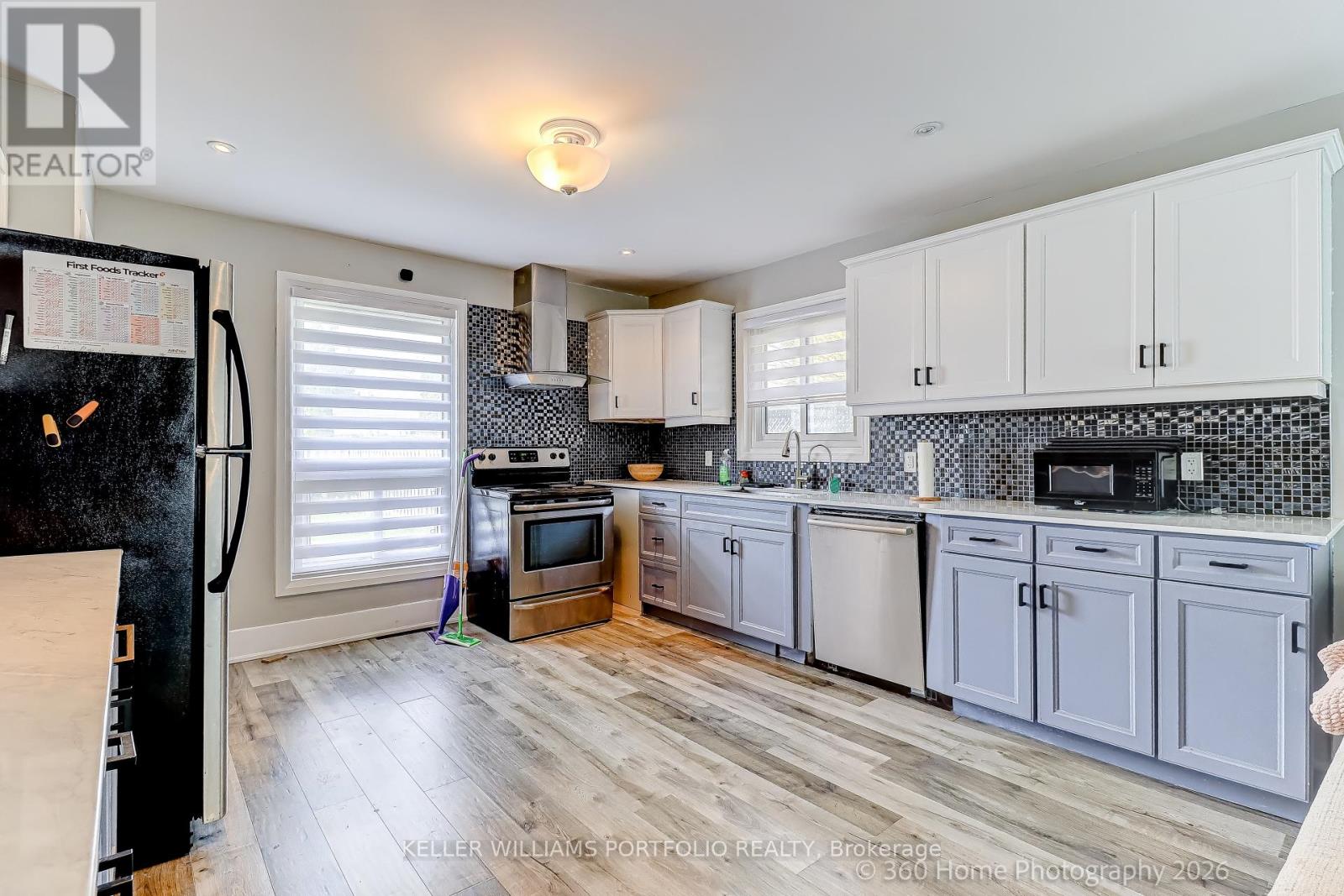A kitchen with white cabinets and a black fridge.
