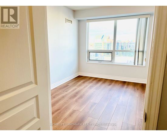 A room with wooden flooring and a large window overlooking a cityscape.