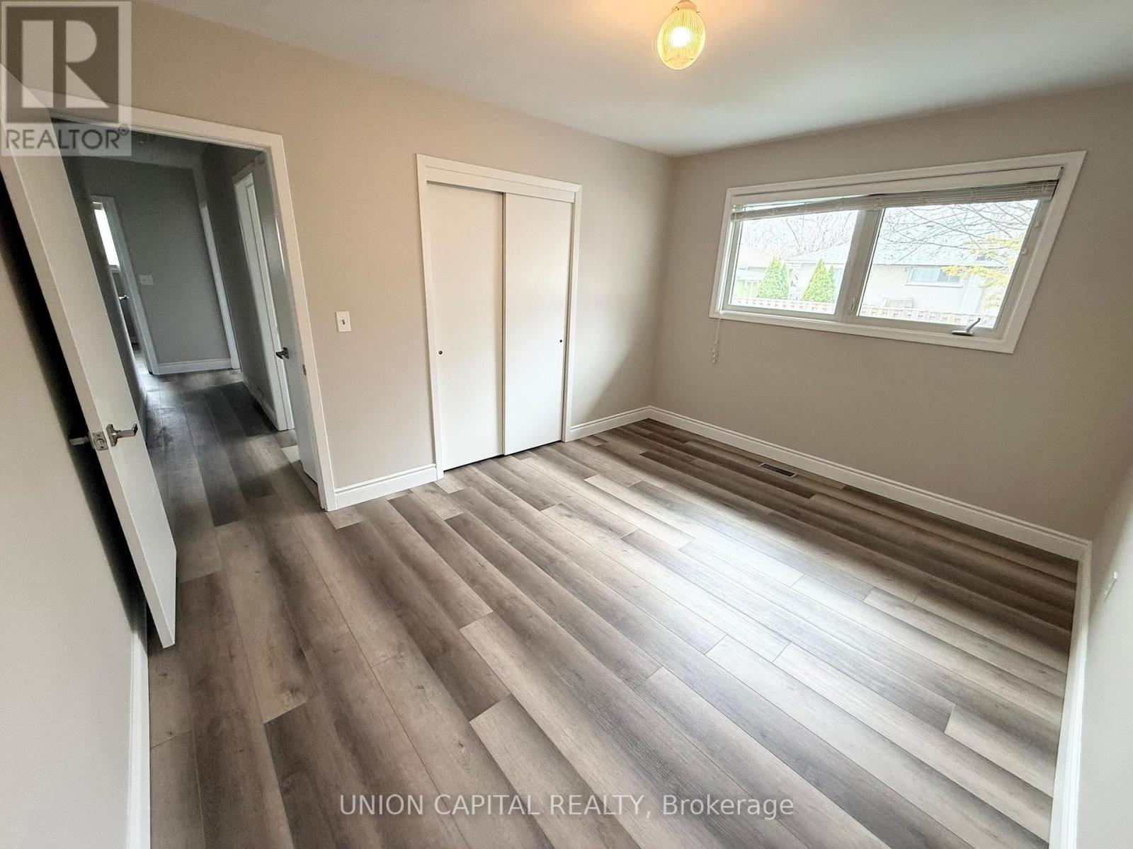 A room with wood flooring and a window with a view of trees outside.