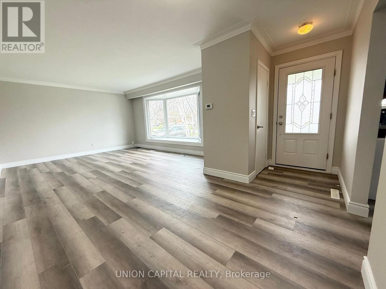 A spacious room with wooden flooring and a white door.
