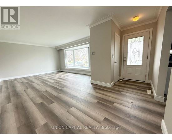 A spacious room with wooden flooring and a white door.