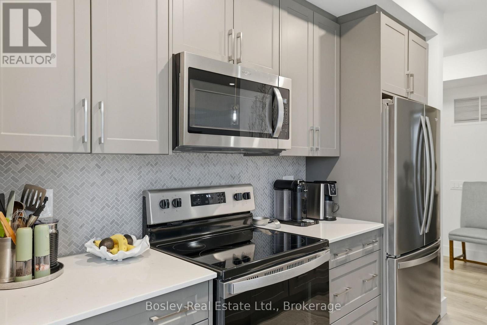 A modern kitchen with a stainless steel refrigerator and microwave above the stove.