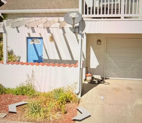 A white house with a blue door and a satellite dish on the roof.