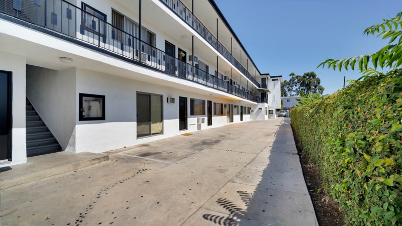 A white building with black railings and a clear blue sky in the background.