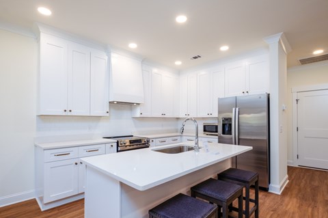 A kitchen with white cabinets and a stainless steel refrigerator.