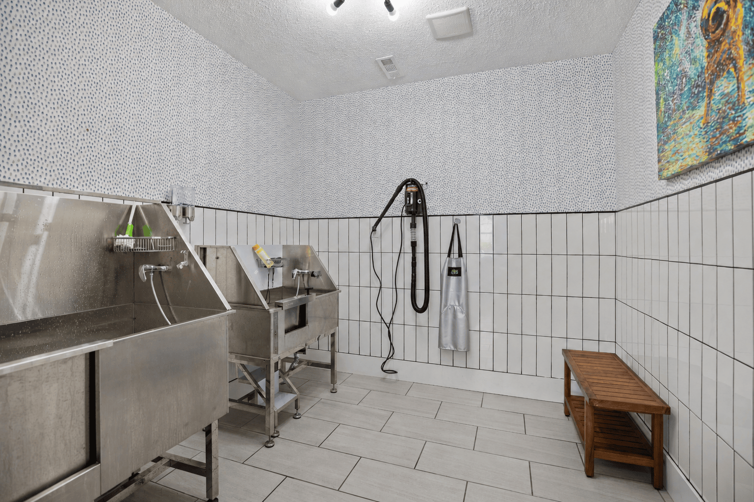 A clean, white tiled bathroom with a shower and a bench.