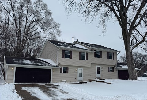 A house with a garage and a driveway covered in snow.