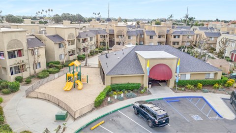 A playground with a slide and a building with a red roof.