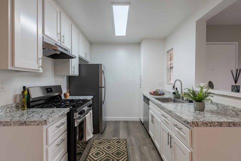 A kitchen with a black refrigerator and a marble countertop.