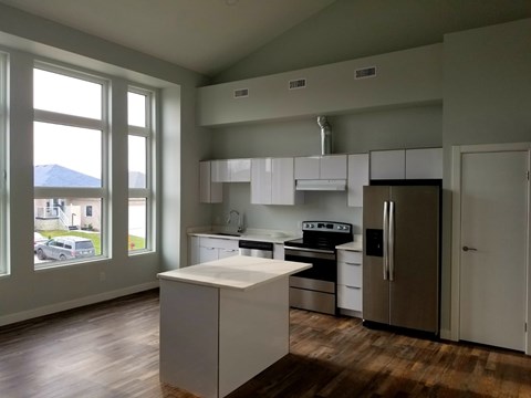 A kitchen with white cabinets and a wooden floor.