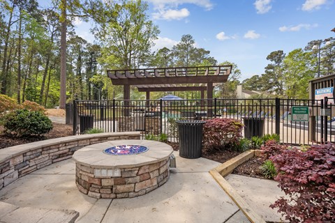 A park entrance with a sign and a circular stone structure in the middle.